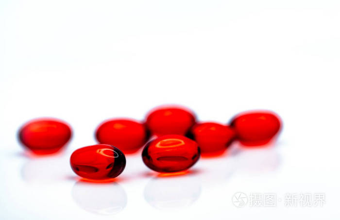 白色背景下分离的红色软凝胶胶囊丸.一堆红色软胶囊.