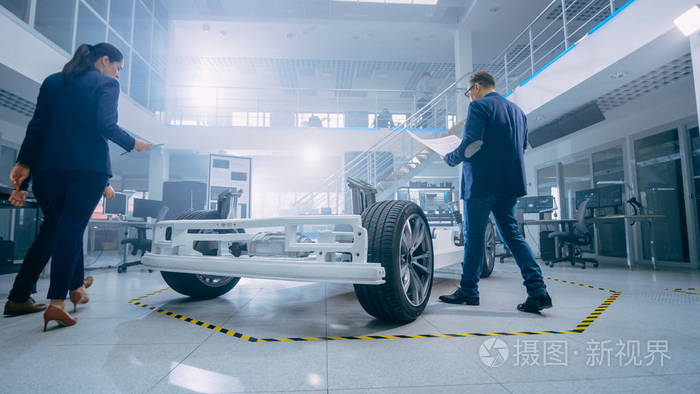 汽车设计工程师在研究电动汽车底盘原型时交谈在创新实验室设施概念车