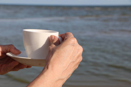 在海边吃羊角面包喝咖啡的女孩图片