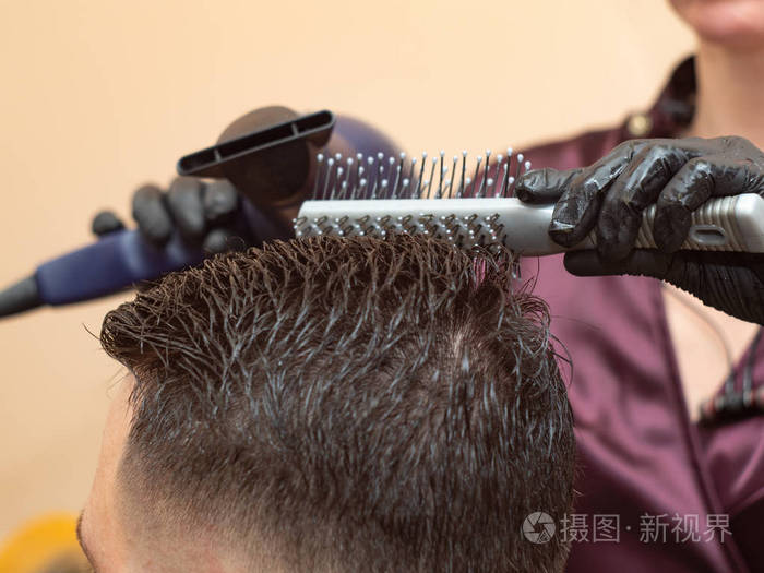精通用圆梳子和吹风机做发型特写戴着橡胶手套的造型师理发师在理发店