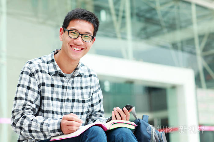 一位年轻的亚洲男大学生在校园里的照片