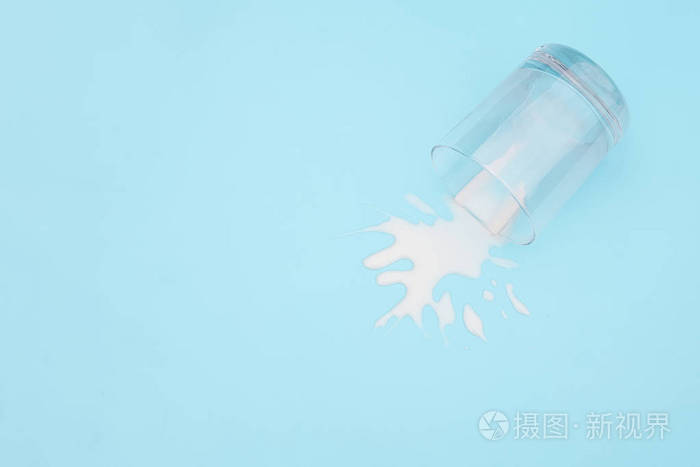 洒了牛奶蓝色背景上有牛奶的翻面玻璃杯乳制品废弃概念复制空间俯视图