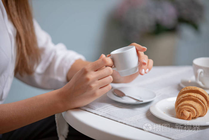 女性手拿咖啡杯的侧视图在法国咖啡馆喝咖啡的女人在法式餐厅喝咖啡的