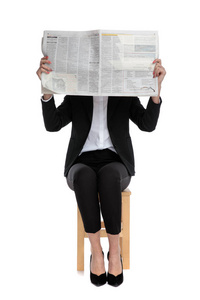 害羞的女商人坐在报纸后面躲着图片