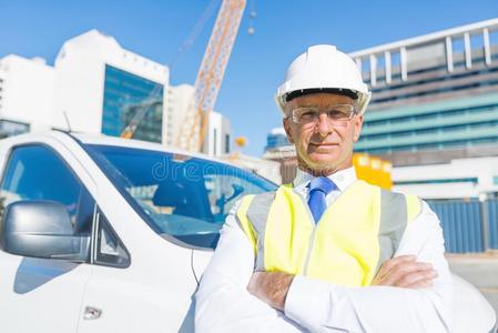 较高的建设者男人在户外在建筑物地点在近处他的汽车int.看