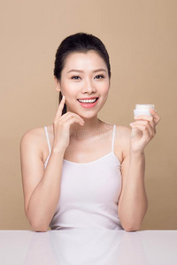 护理皮肤的.美丽的亚洲人女人给看润肤霜或洗液普罗杜