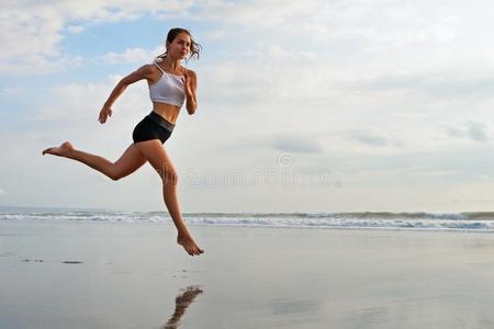 像运动家的女孩跑步在旁边海滩一起海海浪