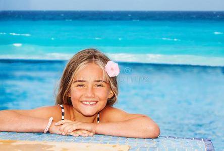 微笑的女孩静止的向指已提到的人边关于游泳水池