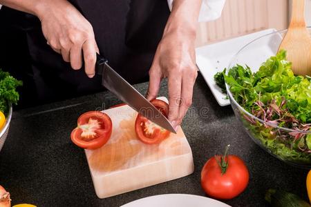 健康的女人使新鲜的蔬菜沙拉和橄榄油,番茄