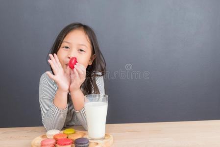 漂亮的小的女孩吃甜的马卡龙