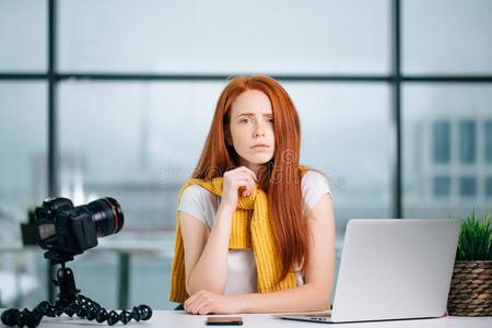 悲哀的红发的人女孩vlogge一次在表和便携式电脑和看着