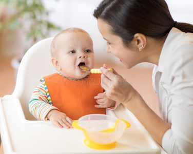 母亲给食她婴儿和勺.母亲礼物健康的食物英语字母表的第20个字母