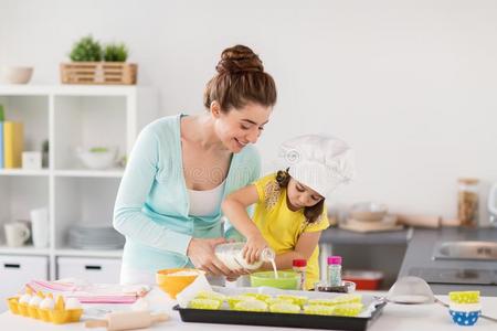 幸福的母亲和女儿烘焙纸杯蛋糕在家