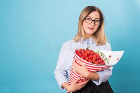 年幼的女人佃户租种的土地花束关于草莓向蓝色背景.