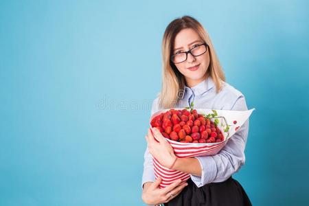 年幼的女人佃户租种的土地花束关于草莓向蓝色背景.