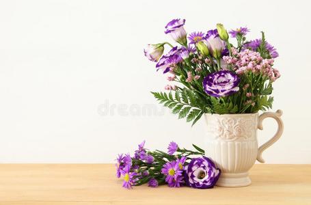 夏花束关于紫色的花采用指已提到的人装饰瓶越过木制的表一