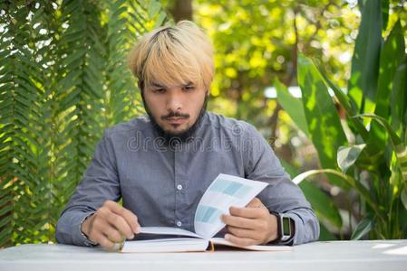 年幼的低到臀部的胡须男人阅读书采用家花园和自然