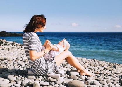 母亲和婴儿演奏在户外向海海滩.