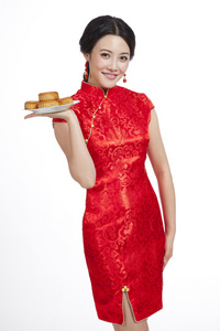 棚拍节日身穿红色旗袍的年轻女人端着月饼