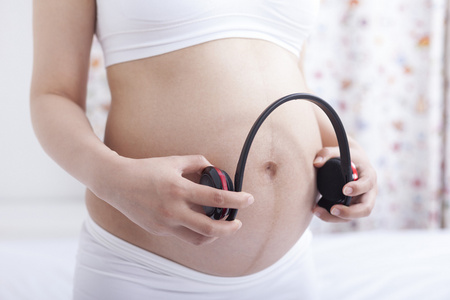 孕妇拿耳机放在肚子上胎教