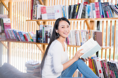 年轻女子在书店看书听音乐