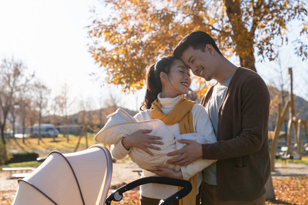 年轻夫妻推着婴儿车散步