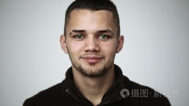 一个年轻的男子,绿色的眼睛,微笑着,在牙齿上显示大括号短视频