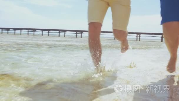 在浅水中运行在沙滩上赤脚夫妇视频