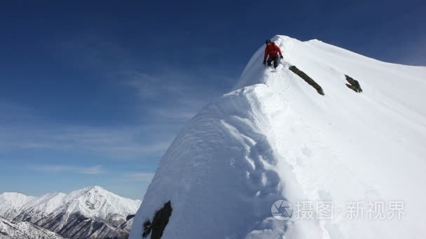 登山者攀登白雪皑皑的山脊视频