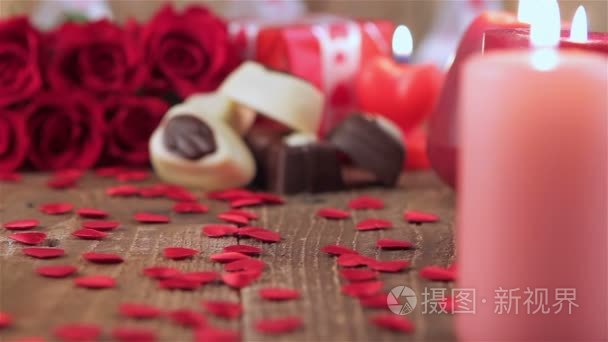 红玫瑰和巧克力糖果，与在木头上的蜡烛