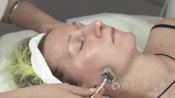 滚子在美容美发美容师使 galvanotherapy 张女人的脸