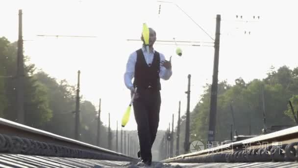在火车铁轨上玩杂耍的家伙。慢动作。日落。在铁路上保持平衡
