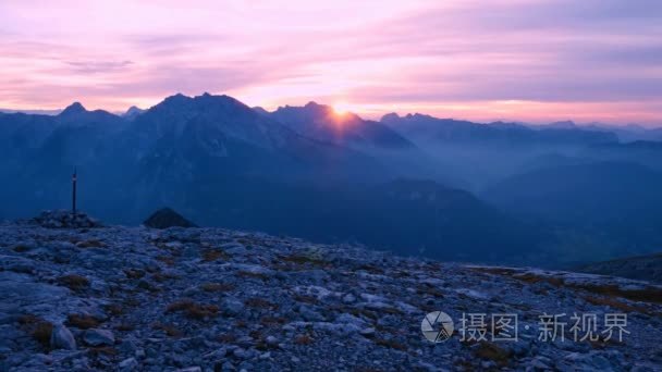 游戏中的山峰落日时光倒流。太阳落在尖峰的阿尔卑斯山。粉色紫色的天空。多彩的 flare 在相机镜头