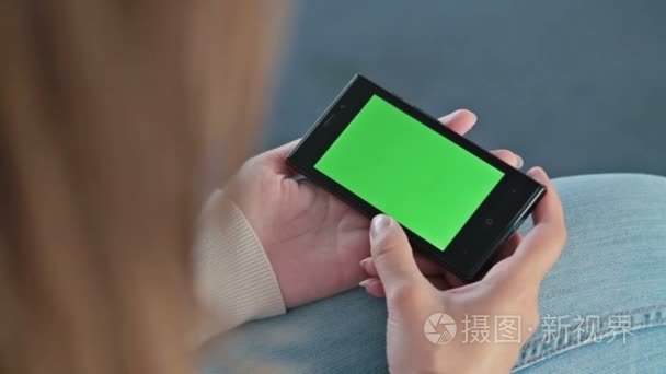 女人拿着智能手机电话与绿屏视频