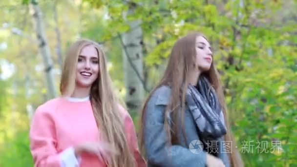 两个白色的年轻时尚女孩留着长头发的性质在秋天跳舞
