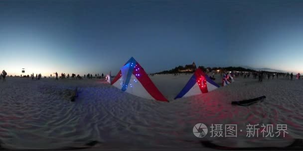 360vr 视频照亮在海蓝色的夕阳的天空人风筝节黄昏莱波兰在沙滩上放风筝七彩灯光三角形的风筝