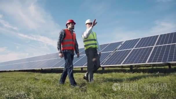 走在一排排的太阳能电池板的工人