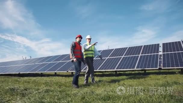 走在一排排的太阳能电池板的工人