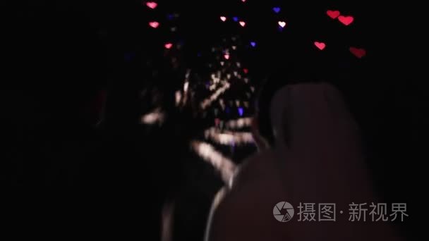 背面的轮廓婚礼夫妇看烟花在夜空中的形式多彩的心