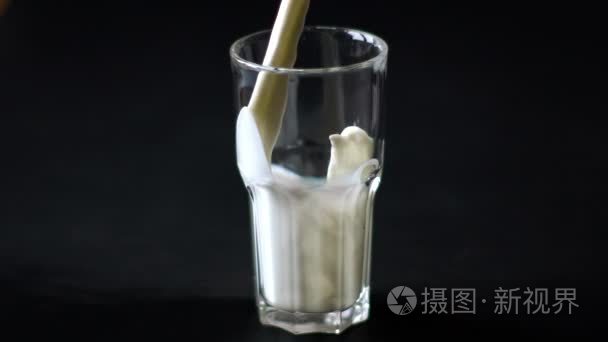 把牛奶倒进玻璃杯在黑色的背景视频