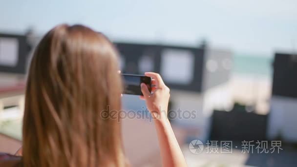 年轻女子拍摄海景与上一款智能手机的架构