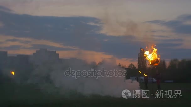 男子亮火剪影周围火黄昏示威游行上边缘的城市住宅房屋绿色草甸春天傍晚日落粉红色的天空