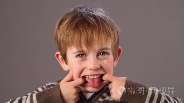 快乐的学龄前孩子做鬼脸，伸出他的舌头