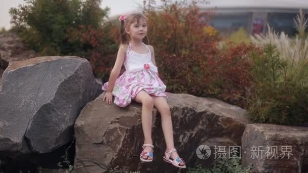 小女孩坐在一块大岩石中万物的歌唱和微笑