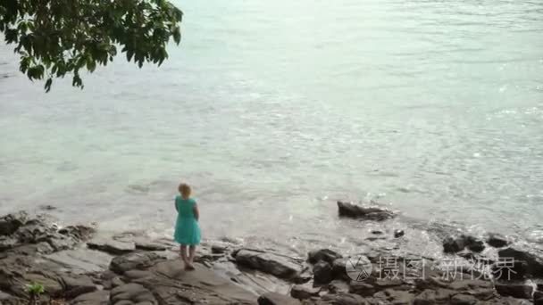 岩石的海滩上的年轻女子视频