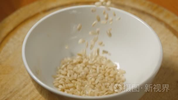 整个水稻谷粒落在白色的陶瓷碗视频