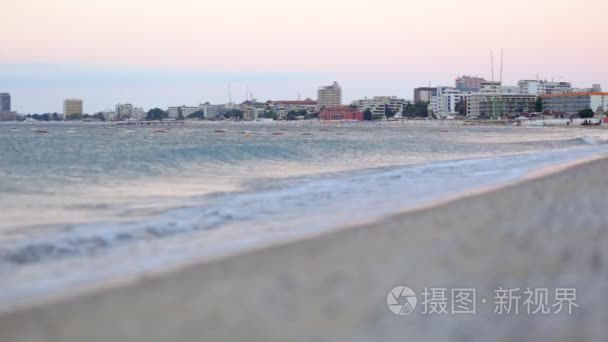 在阳光明媚的海滩，在日落时海里的特写平静浪