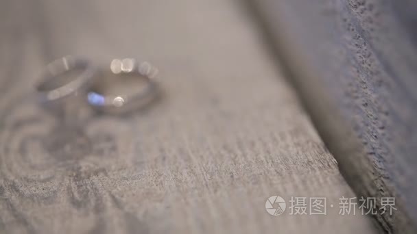 两个白色的金戒指，这张照片拍摄户外木制的桌子上