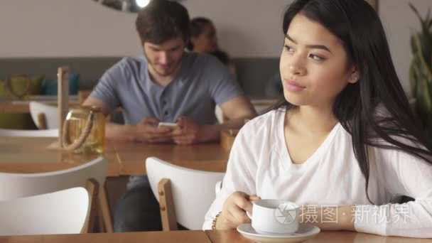 女孩靠她的下巴在她的手坐在咖啡馆里