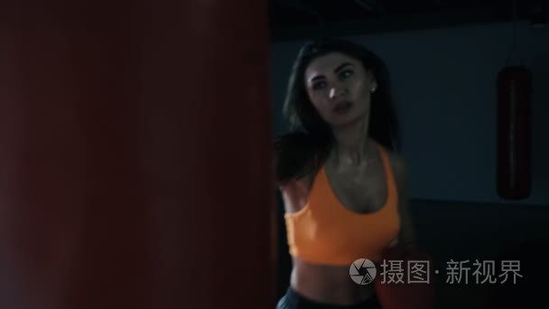 年轻女子拳击沙袋在黑暗的大厅视频